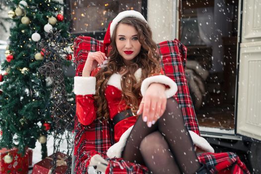 Young woman in santa costume resting at winter campsite. New year celebration concept