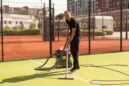 The boy cleaning tennis court clay surface after the match to prepare for the next match.