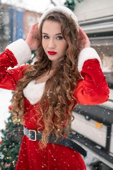 Young woman in santa costume resting at winter campsite. New year celebration concept