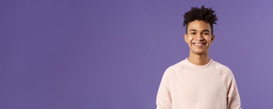 Close-up portrait of cheerful young hipster guy with dreads, smiling optimistic and delighted, standing purple background, having lucky good day, express positivity and joy.