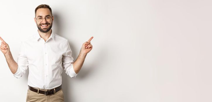 Confident bearded man smiling, pointing left and right at copy spaces, standing over white background.