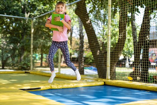 girl with books jump on a trampoline.