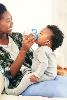 Juice does the body good. a mother giving her little baby boy a bottle