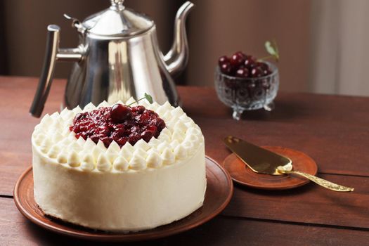 Biscuit cake, cherry souffle with cream cheese and cherry confiture on wooden background copy space