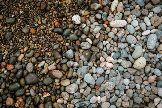 Pebble beach stones background, natural rounded gravel on the seashore nature background texture pattern. Wet pebble stones on the beach