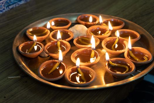 Brass plate filled with eartheware diyas filled with oil and a cotton wick lit for light in India