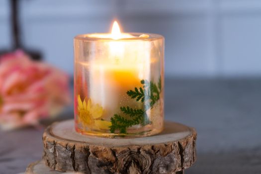 Lit resin art transparent candle on wood coaster with flowers showing the decoration of diwali, christmas, new year shot in pastel shades