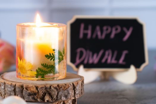 small transparent resin art candle lit with cute chalk board with happy diwali written on it for the festival of light