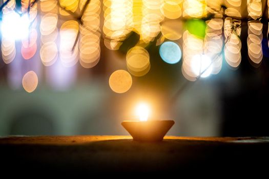 lone earthenware oil lamp diya set against colorful bokeh balls showing the lighting and decoration during the hindu festival of diwali showing a serene peaceful vision in the night India