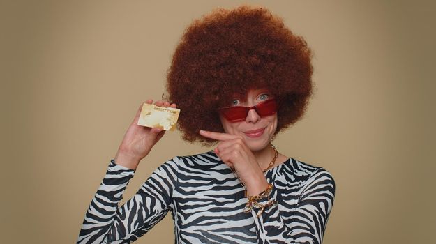 Happy woman showing plastic credit bank card advertising transferring money cashless, purchases online shopping, sale discount, internet order delivery purchase. Adult stylish girl on beige background