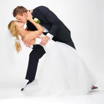 Wedding, couple and love with a kissing man and woman after marriage in studio on a white background. Young bride and groom at a celebration event together, happy and romantic in a dress and suit.