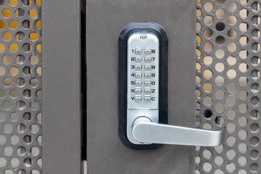 Locked private metal security gate door with push button combination lock system keypad with metallic silver doorknob handle