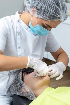 Patient with cheek retractor lying in dentist office in modern clinic