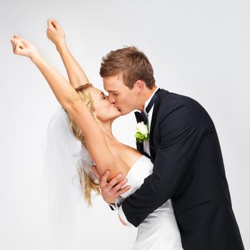 Love, wedding and happy couple kiss at their marriage reception on a white studio background. Man, woman or bride and groom in celebration of their commitment, union or luxury romantic event.