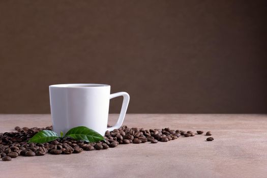 A white porcelain coffee cup with a saucer stands on a brown surface near scattered coffee beans. Selective focus.