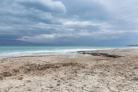 Exotic view of the sinkhole area of the Dead Sea on a stormy winter day. PhotoStorm and rain at the Dead Sea coastline. Salt crystals at sunset. The texture of the Dead sea. Salty seashore. High quality photo