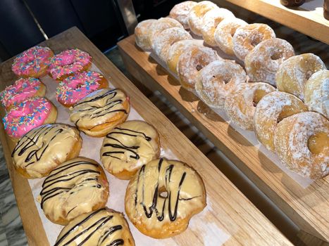 Lines of fresh delicious donuts on bakery shop, tasty multiple donuts, Selective focus donuts with various topping