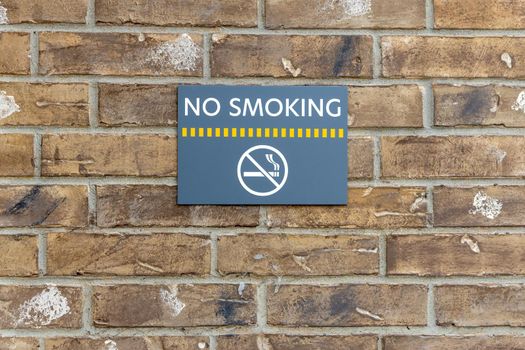 No smoking sign on the building, warning sign on the brick wall background, information about ban of smoking