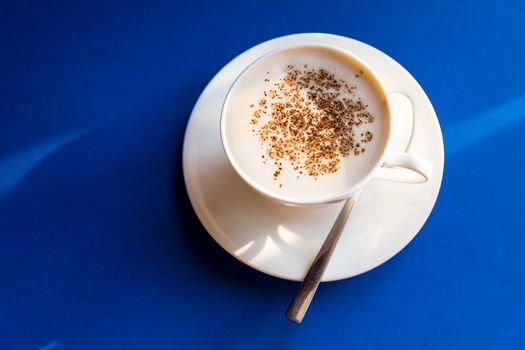 Cappuccino Flat lay, black background, white cup with spoon, coffee beans. Morning coffee in Italy. Close-up on a white cup.