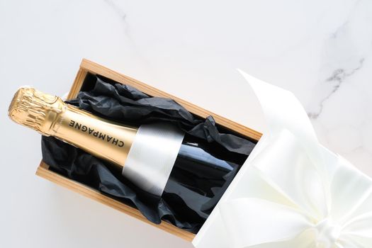 Wedding celebration, lifestyle and luxury present concept - A champagne bottle and a gift box on marble