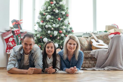 family near the Christmas tree in their living room.
