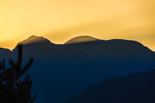 Sunrise in the mountains. Black silhouettes of mountain peaks.