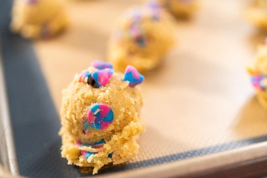 Chilled cookie dough scoops on the baking sheet to bake unicorn chocolate chip cookies.