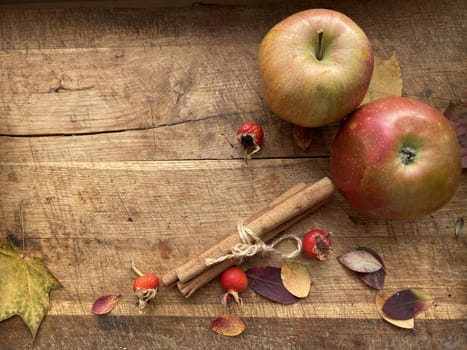 Fresh ripe red apples and cinnamon sticks on wooden background.