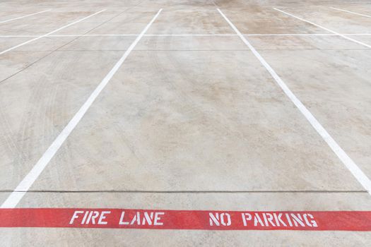 Fire lane no parking marking on the road of a parking lot, red line with white inscription on the asphalt, car parking is prohibited