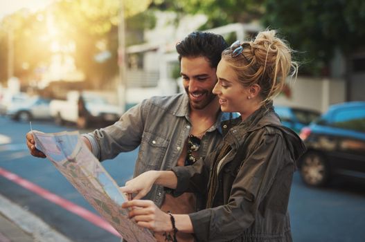 To travel is to live. a young couple using a map while exploring the city