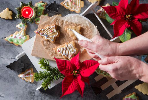 female hands decorate shortbread Christmas cookies with icing, cookies in the form of New Year's figures
