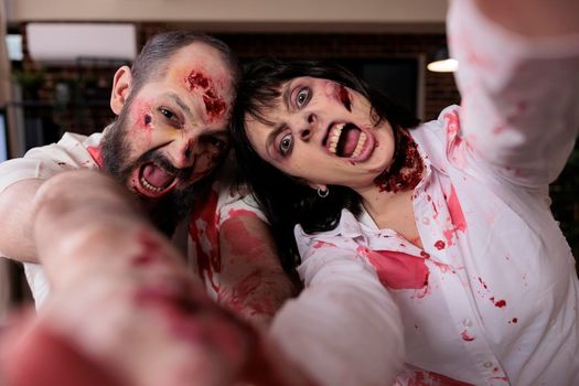 Portrait of scary zombies couple in business office, hunting people to eat brain and looking evil terrifying. Aggressive dangerous walking dead corpses eerie monsters attacking workplace.