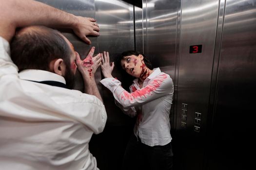 Couple of zombies trying to escape elevator, brain eating evil monsters attacking workplace. Creepy spooky undead walkers with bloody dirty wounds, looking scary and gory terrifying.