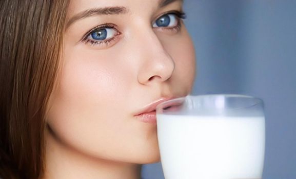 Happy young woman with glass of milk or protein milk shake, healthy cocktail drink for diet and wellness concept