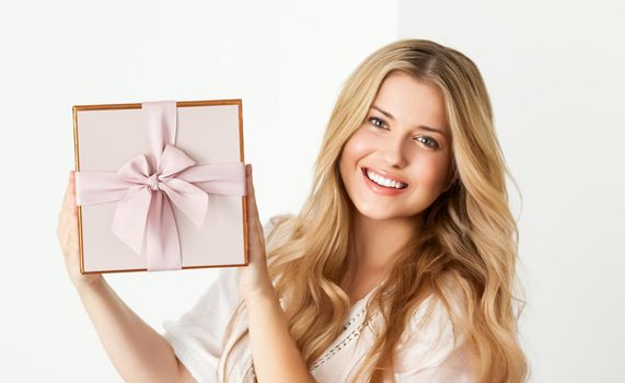 Holiday present for birthday, baby shower, wedding or luxury beauty box subscription delivery, happy woman holding a wrapped pink gift on white background