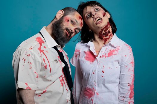 Portrait of zombies couple posing on camera, looking undead and creepy with bloody wounds or ugly scars. Apocalyptic monsters with dirty scratches acting dangerous and aggressive.