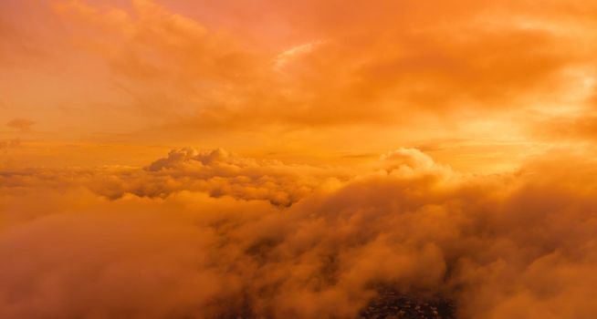 A red burning sunset with the silhouette of a cliff over the sea. Abstract nature summer or spring ocean sea background. Small waves on golden warm water surface with bokeh lights from sun.