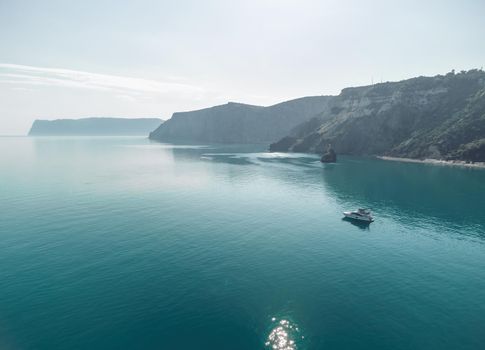 Aerial boat race. Luxury cruise trip. View from above of white boat on deep blue water. Aerial view of rich yacht sailing sea. Motor boat racing wave. Summer journey on luxury ship