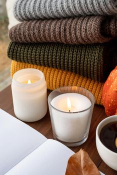 Hello fall. Cozy warm image. High angle view autumn composition with sweaters and candles, mockup design