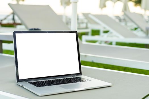 Computer laptop with blank screen near the swimming pool