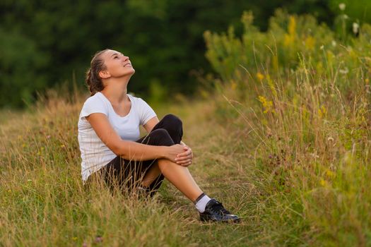 sporty dressed woman sitting on green lawn