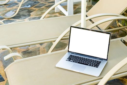 grey laptop computer open with keyboard on deckchair.