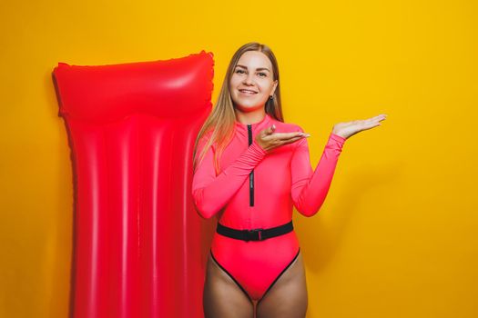 Young woman slim body pink one piece swimsuit on pink air mattress isolated on bright yellow color studio background summer hotel swimming pool sea vacation sun tanning concept. Place for text