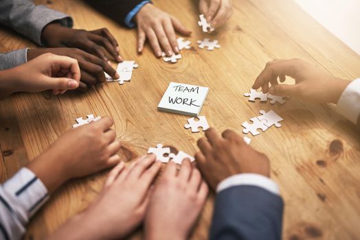 All the pieces are falling into place. High angle shot of a group of unrecognizable coworkers building a puzzle on their boardroom table
