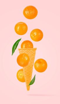 Isolated ice cream cone with fruits in the air. Seven falling whole tangerines on pastel pink background with clipping path as package design element and advertising. Full depth of field.