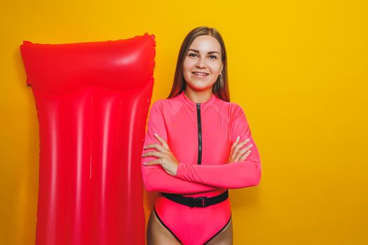 Young woman slim body pink one piece swimsuit on pink air mattress isolated on bright yellow color studio background summer hotel swimming pool sea vacation sun tanning concept. Place for text
