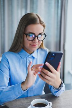 Smart female employee with netbook looking at camera during mobile call, successful freelancer in jacket talking on phone via app