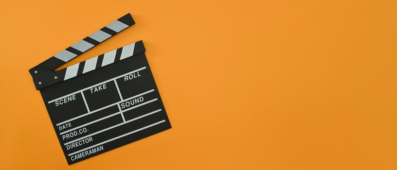 A clapper board on orange background with copy space. Cinema minimal concept.