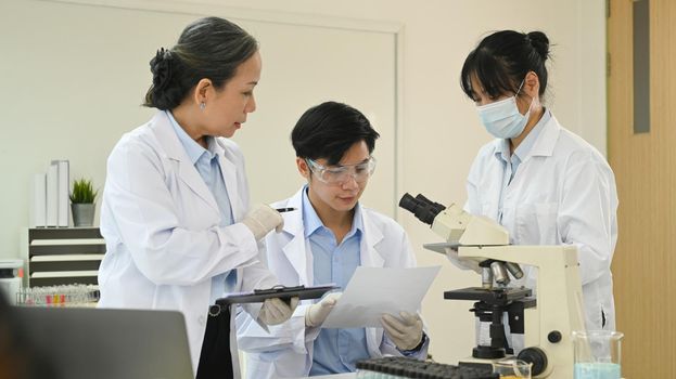 Team of professional biotechnology specialist conducting experiment in a laboratory. Concepts of medicine and science researching.