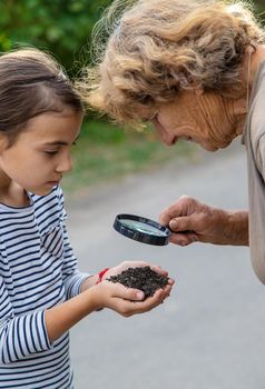 The child examines the soil with a magnifying glass. Selective focus. Kid.